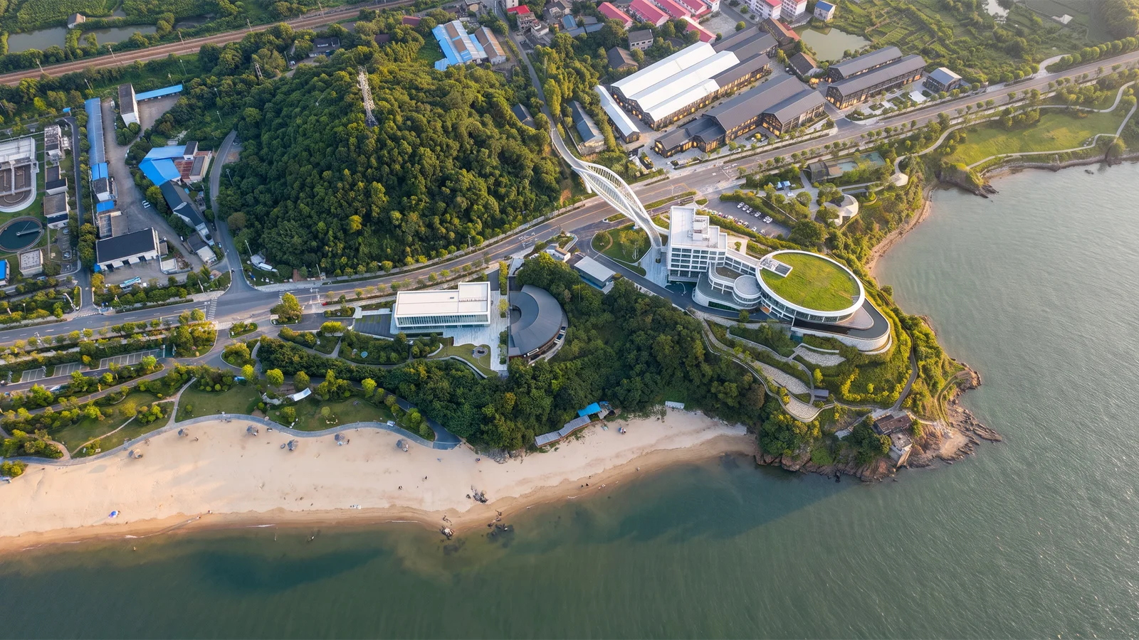 滨水建筑与步道围绕水面展开，呈现文旅公共空间的鸟瞰景观
